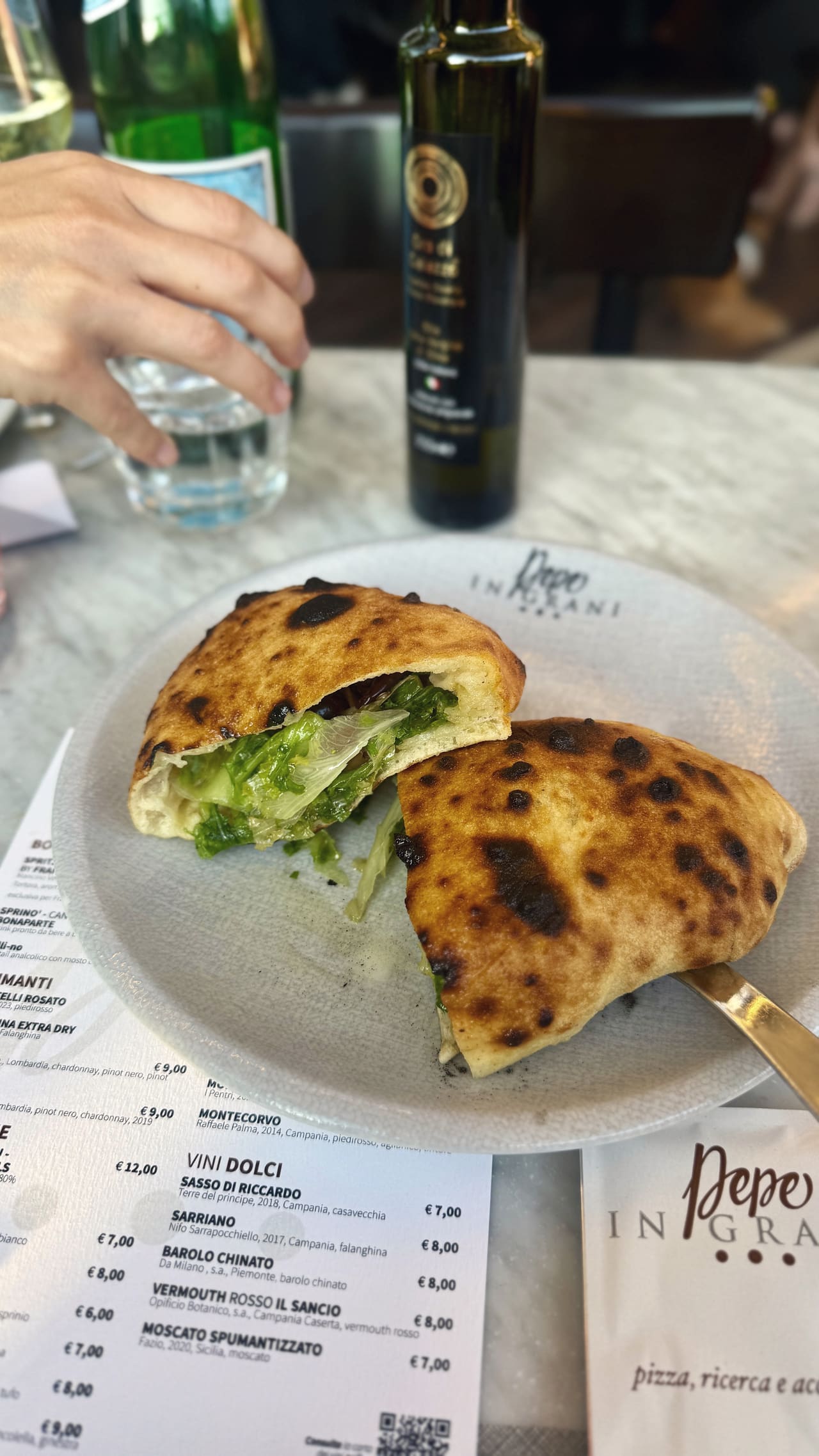 A calzone cut in half on a Pepe in Grani plate, the blistered crust opened to show the escarole inside